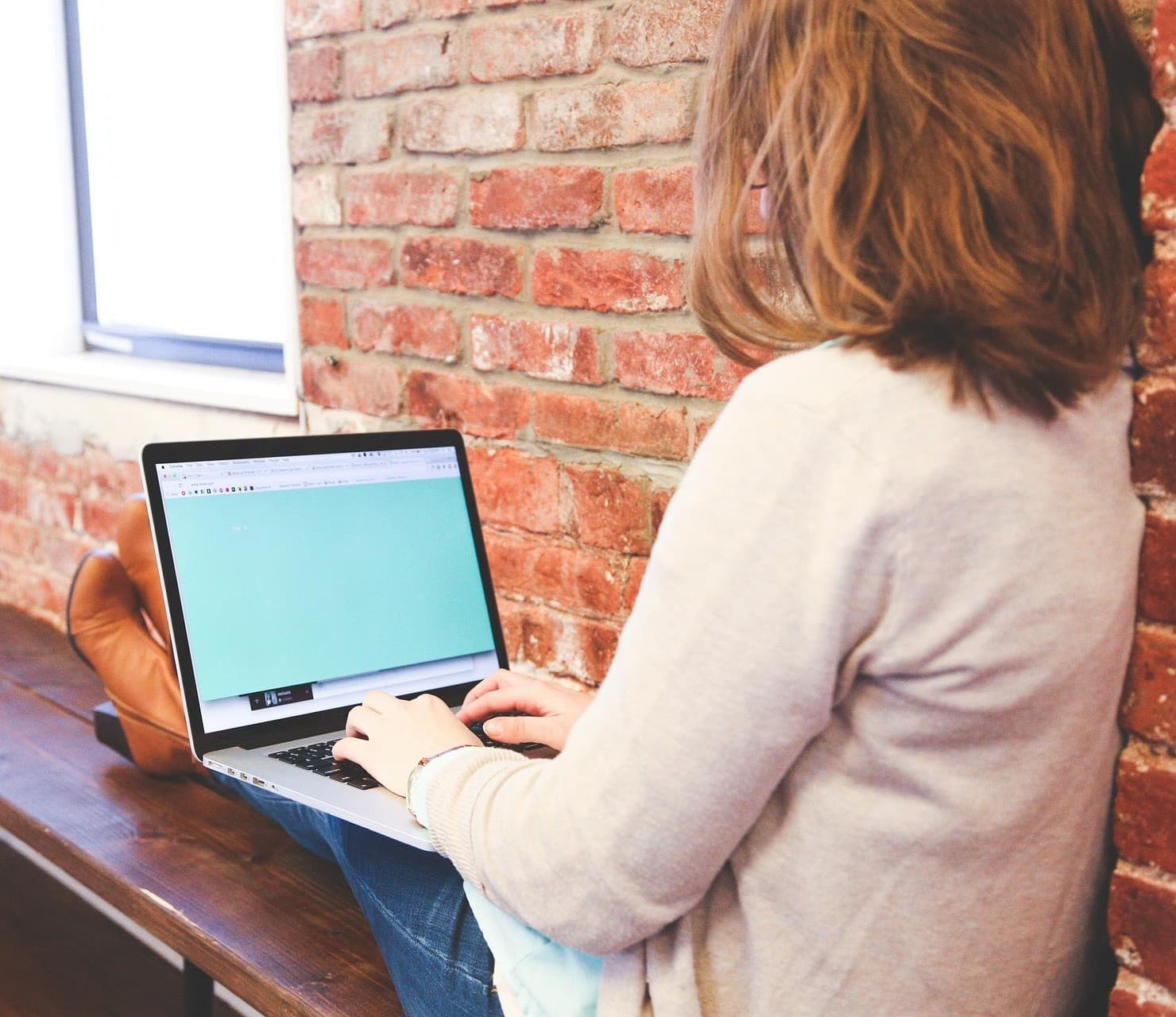 Student sitting on a bench with a laptop on her lap.